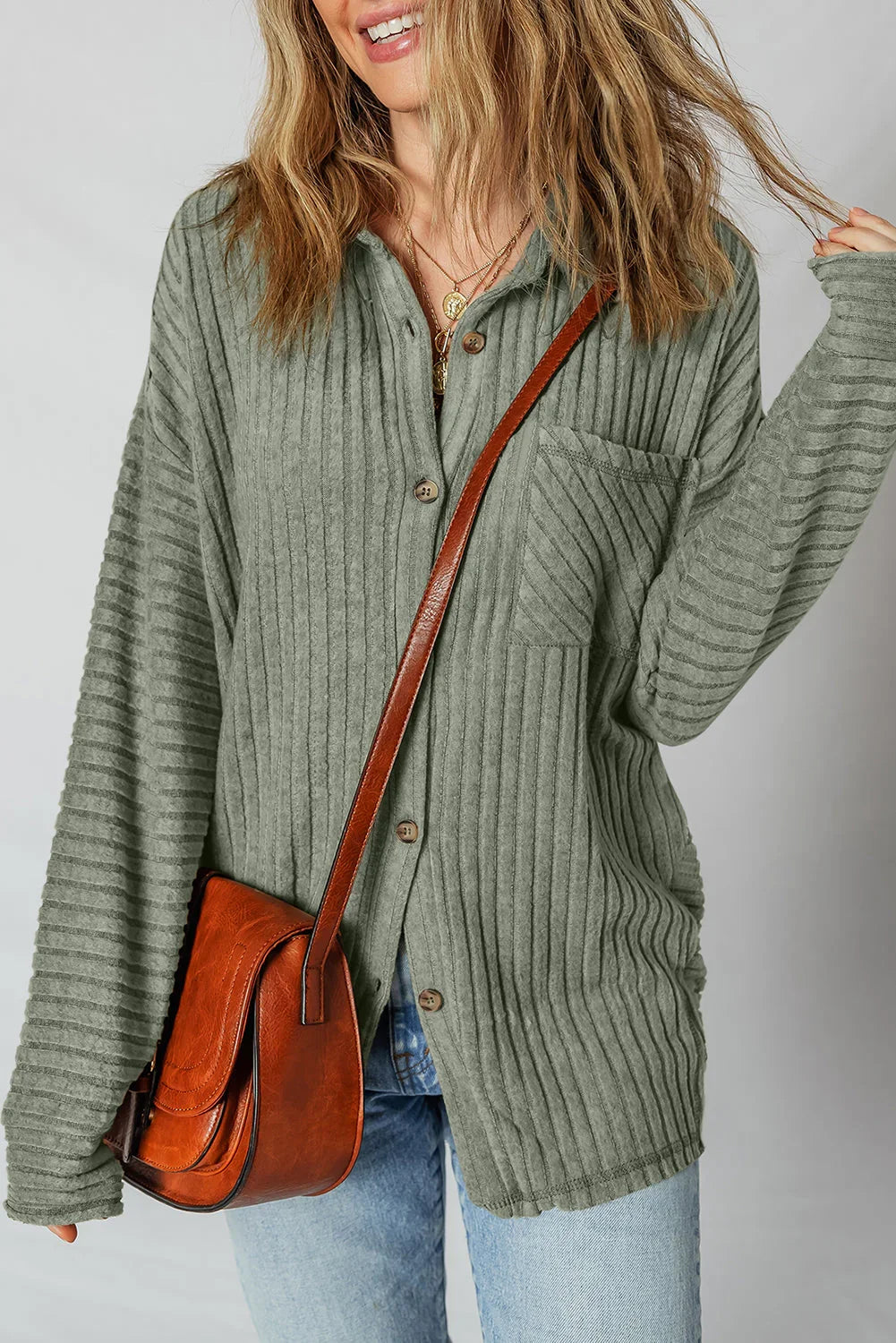 Woman wearing an olive ribbed button-up shirt with jeans and a brown crossbody bag