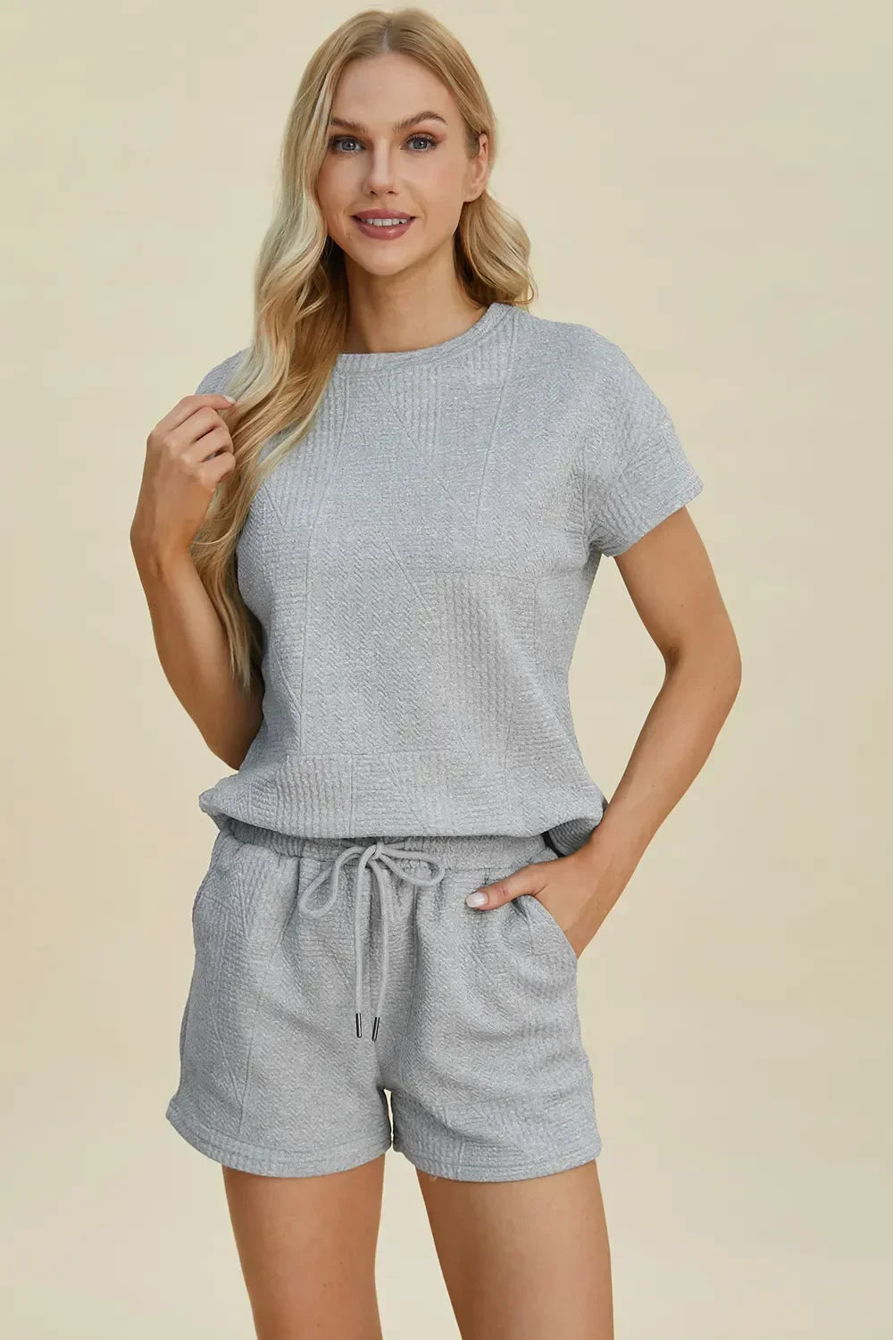 Woman wearing a light grey short-sleeve textured lounge set with drawstring shorts