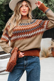 Woman in fair isle knit sweater, wide-brim hat, blue jeans, and holding woven brown bag outdoors