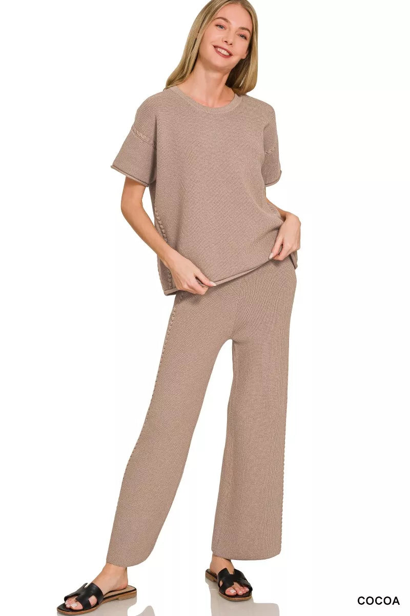a woman wearing a taupe viscose round neck top pants set with black slides on a white background
