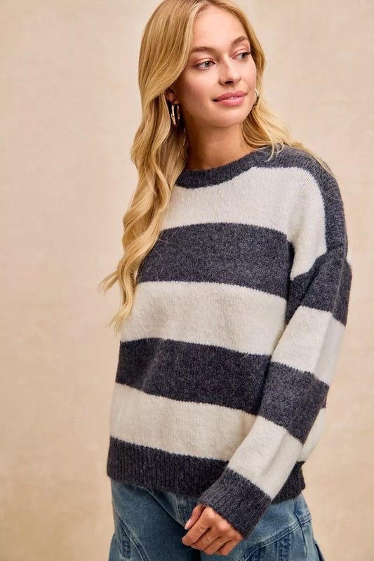 Woman wearing a cozy gray and white striped sweater with relaxed fit and casual blue jeans