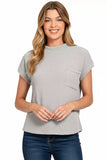 Woman wearing a light grey textured short sleeve top with chest pocket and blue jeans