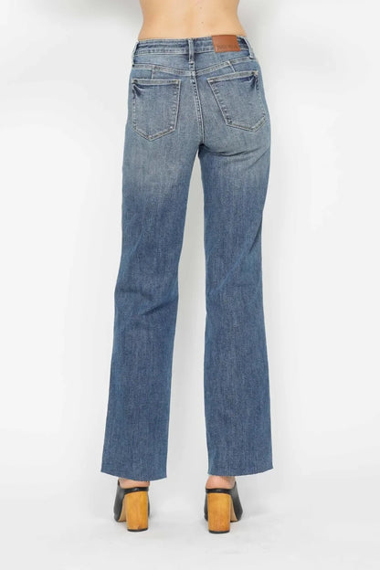Back view of straight-leg blue denim jeans with pockets and brown block heel shoes