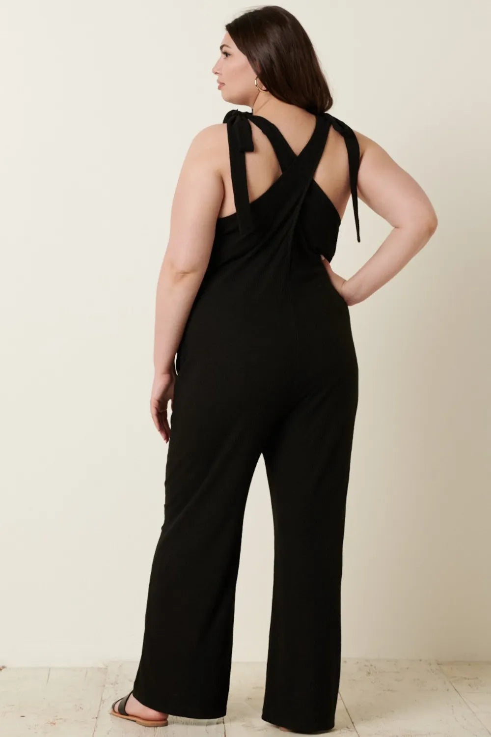 Woman in black wide-leg jumpsuit with cross-back and tie shoulder straps