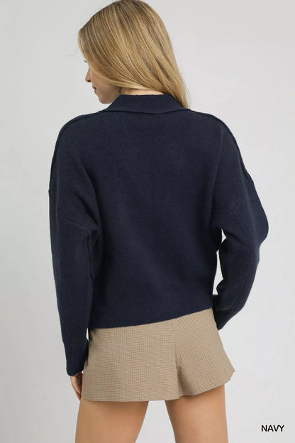 Woman wearing navy sweater and beige plaid mini skirt, back view, minimal background
