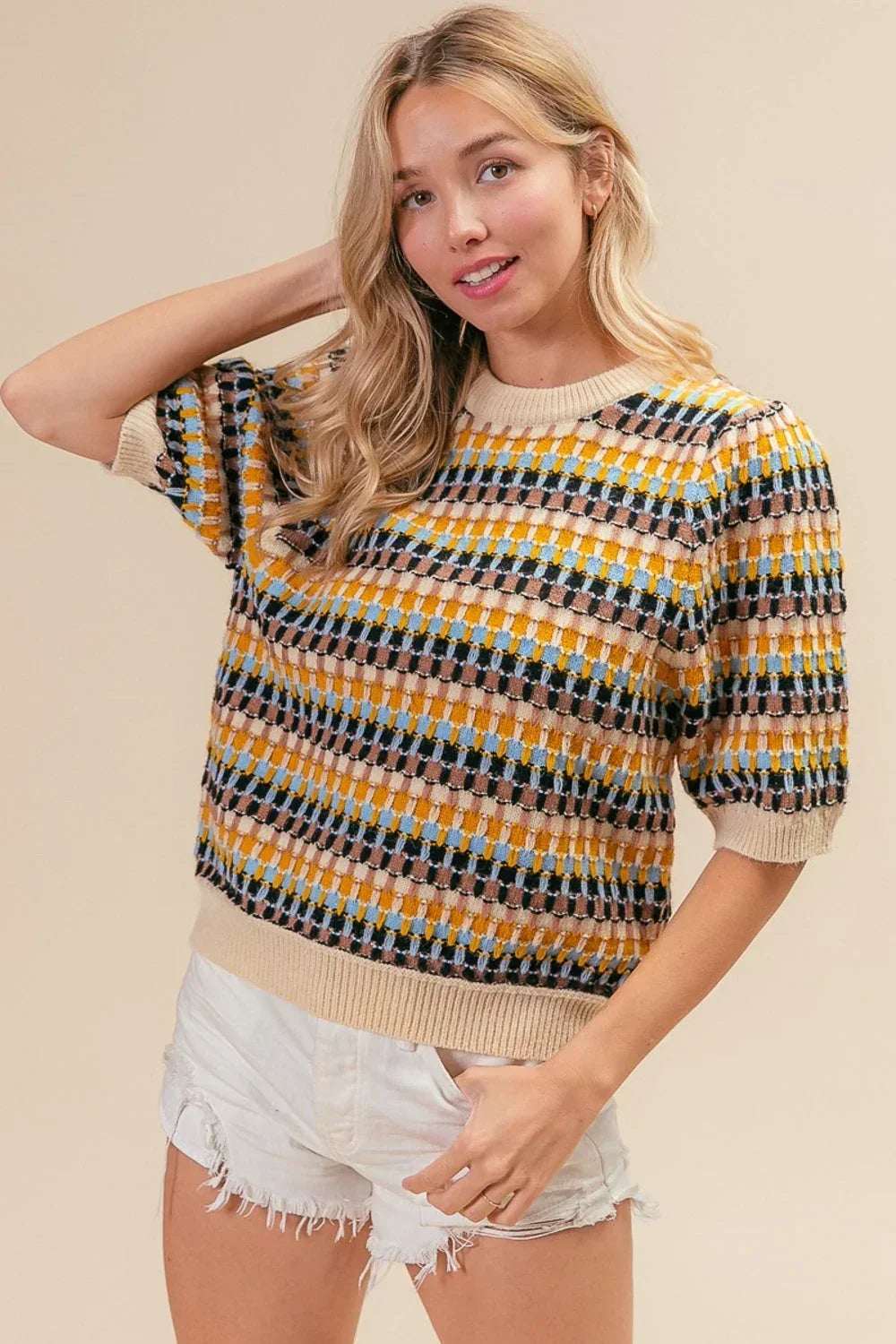 Woman wearing a multicolor short-sleeve knit sweater and white distressed shorts