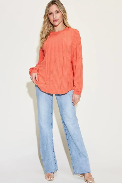 Woman wearing relaxed orange ribbed long sleeve top and light wash wide-leg jeans