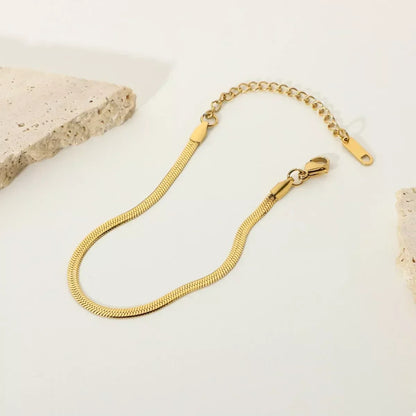 Gold herringbone chain bracelet with adjustable clasp on a minimalist neutral background