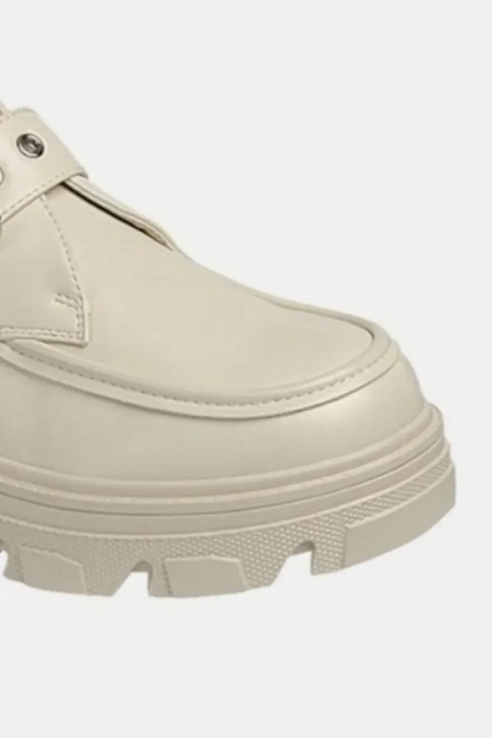 Close-up of beige chunky platform loafer with textured rubber sole on white background