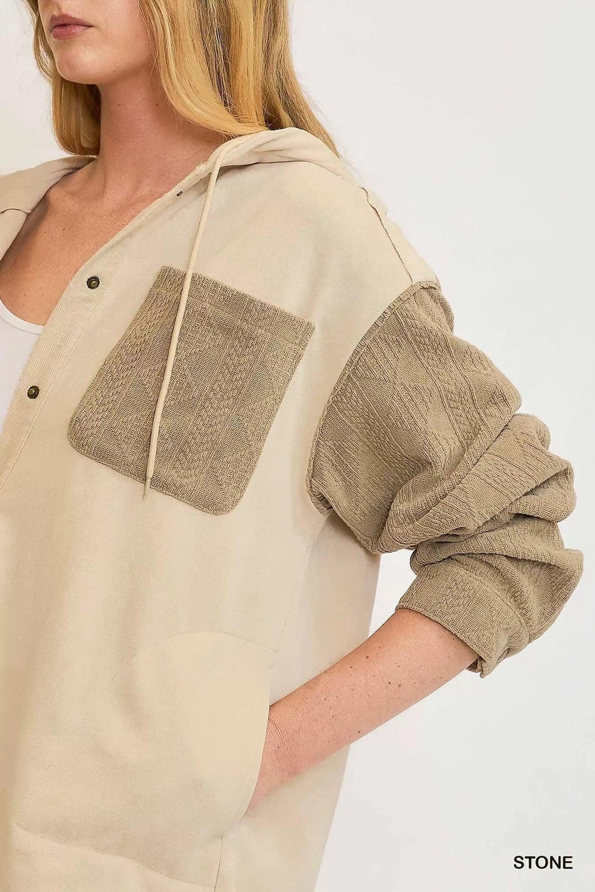 Woman wearing a beige hooded jacket with textured tan pocket and sleeves, relaxed fit