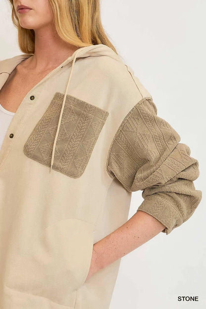 Woman wearing a beige hooded jacket with textured tan pocket and sleeves, relaxed fit