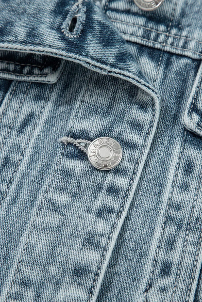 Close-up of light wash denim jacket with silver button and textured stitching detail