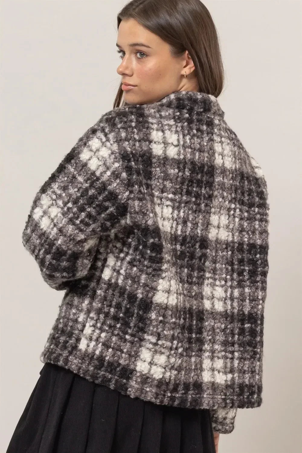 Woman wearing a textured black and white plaid cropped jacket with relaxed silhouette.