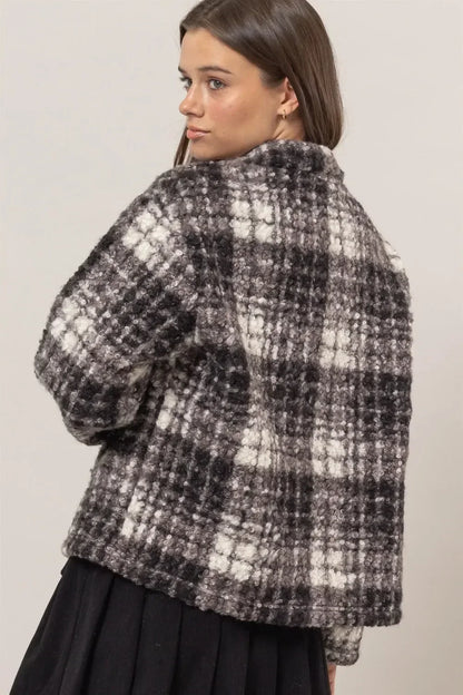 Woman wearing a textured black and white plaid cropped jacket with relaxed silhouette.