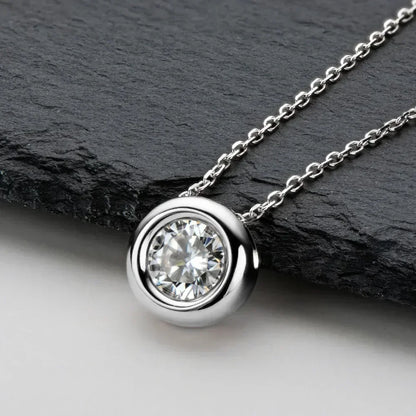 Silver bezel-set solitaire pendant necklace with round clear gemstone on a chain