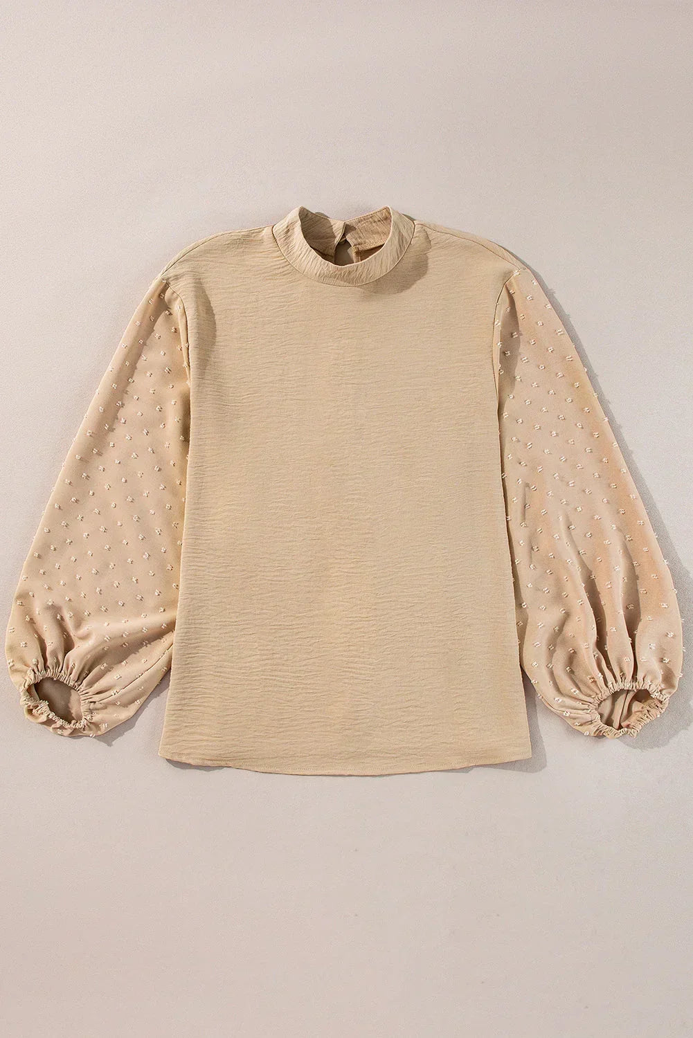 Beige blouse with textured sheer bishop sleeves and mock neck on neutral background
