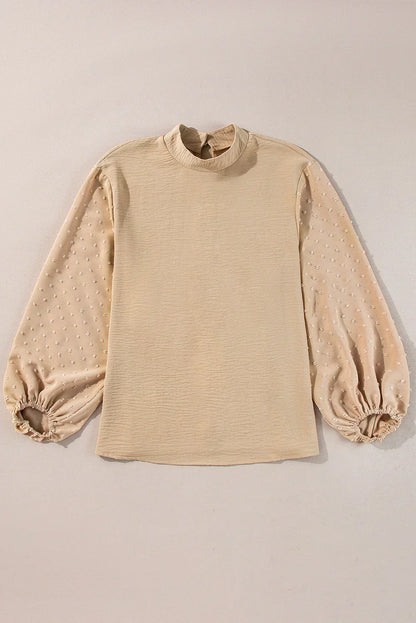Beige blouse with textured sheer bishop sleeves and mock neck on neutral background