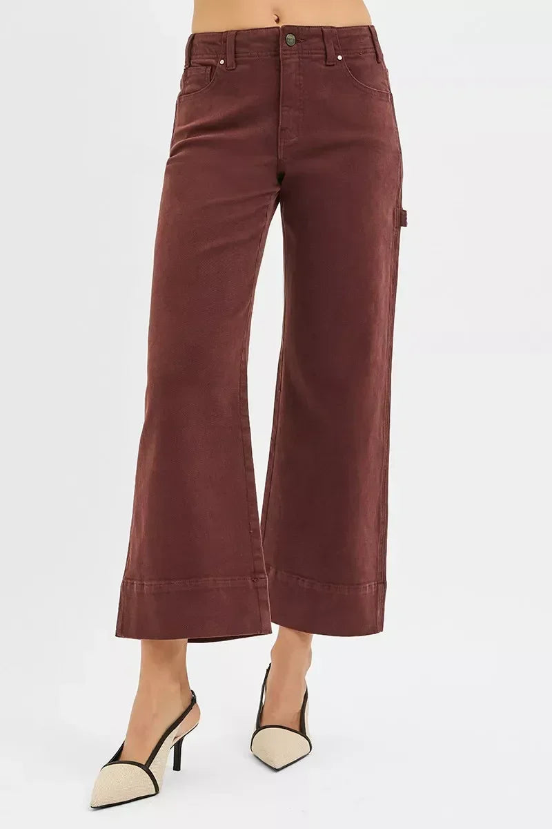Woman wearing high-waisted wide-leg brown pants and beige heels against a white background