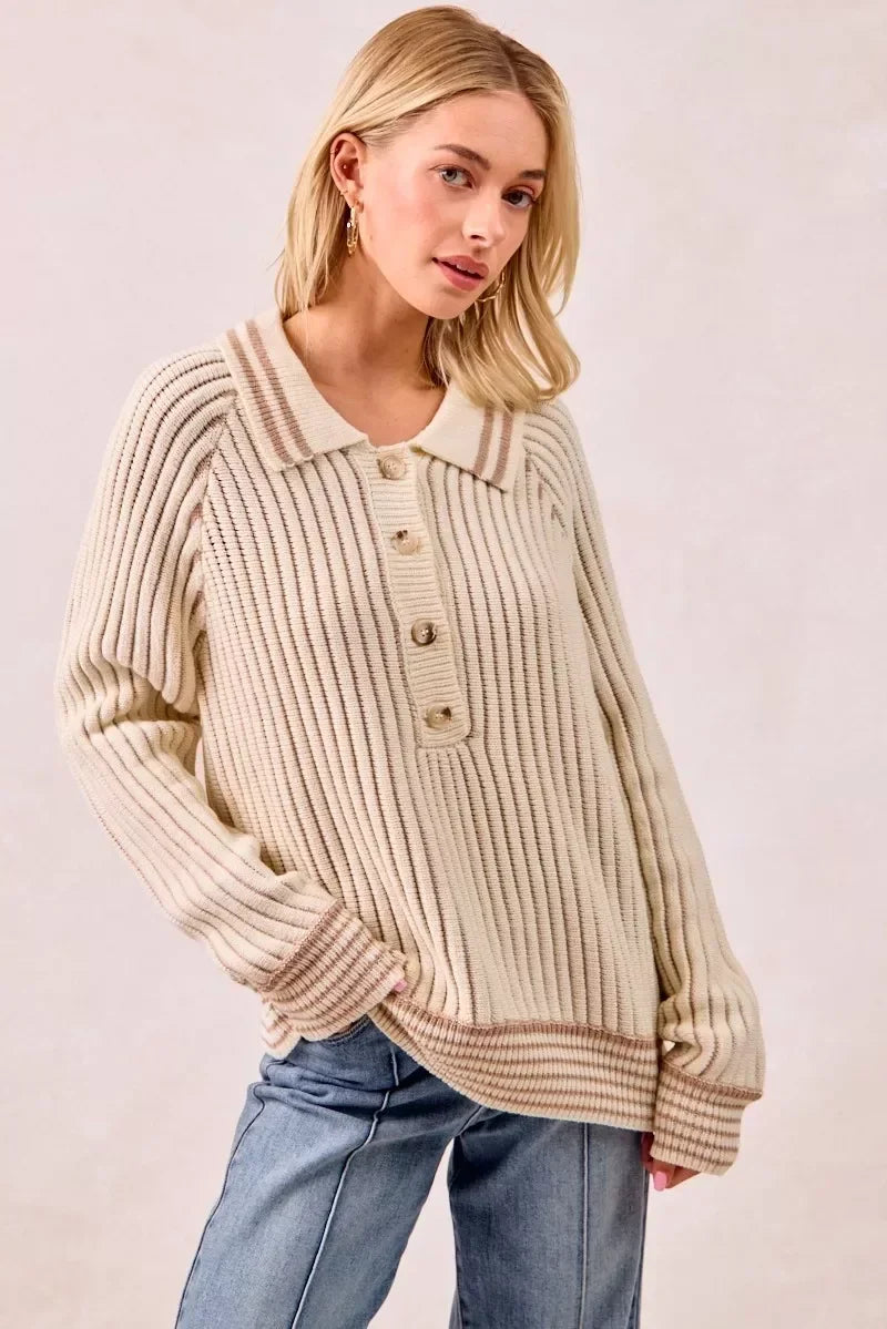 Woman wearing cream ribbed knit pullover with collar, button front, and striped trim, styled with jeans.