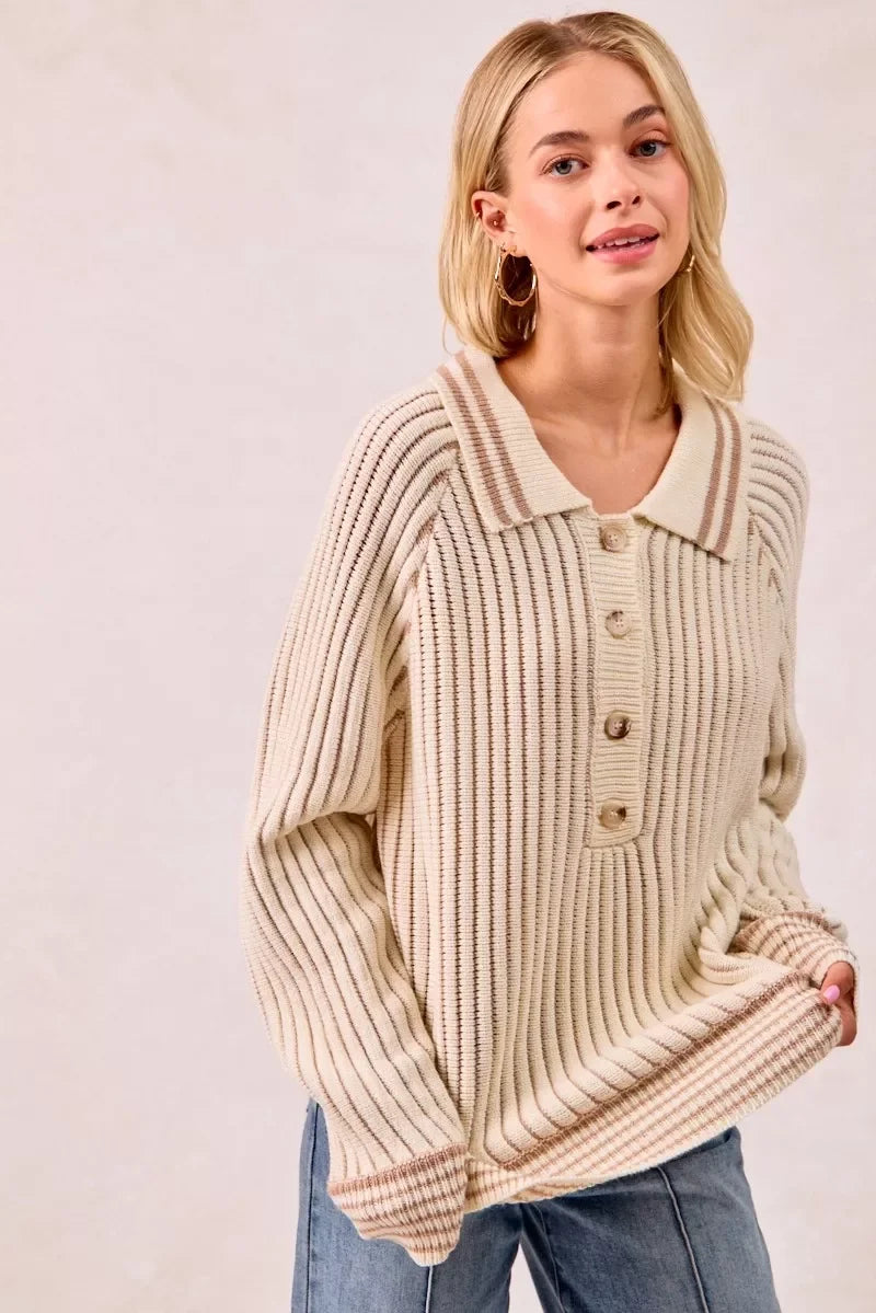 Woman wearing a ribbed cream knit sweater with buttons and collared neckline, paired with jeans