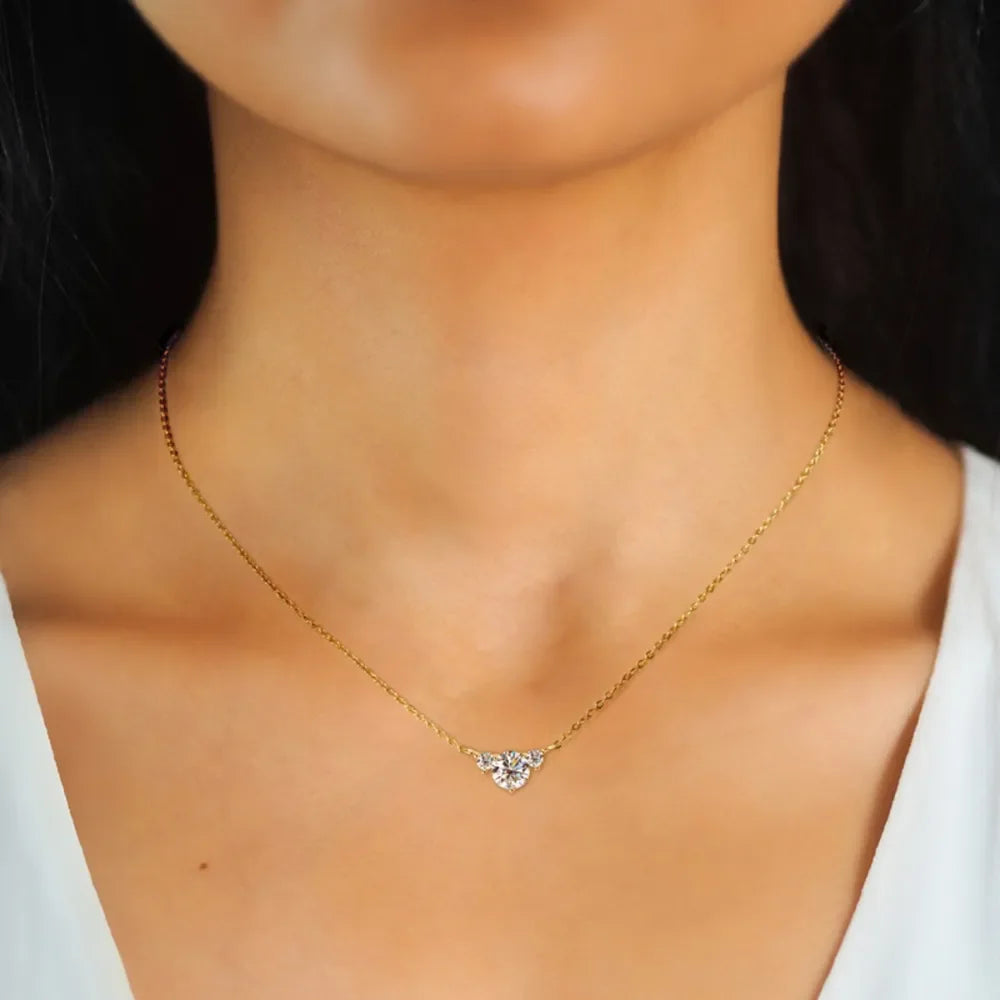 Gold chain necklace with small diamond pendant on woman wearing white top