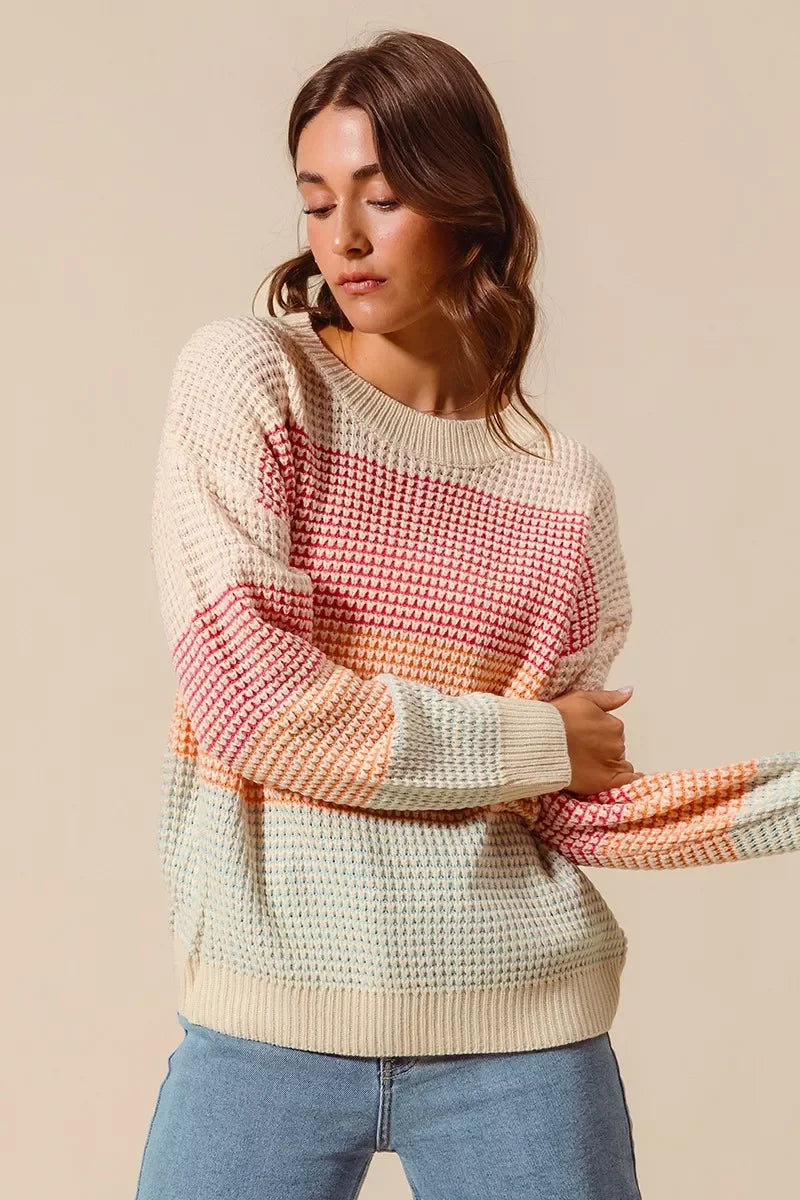 Woman wearing a relaxed fit multicolor striped knit sweater and light blue jeans