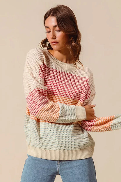 Woman wearing a relaxed fit multicolor striped knit sweater and light blue jeans