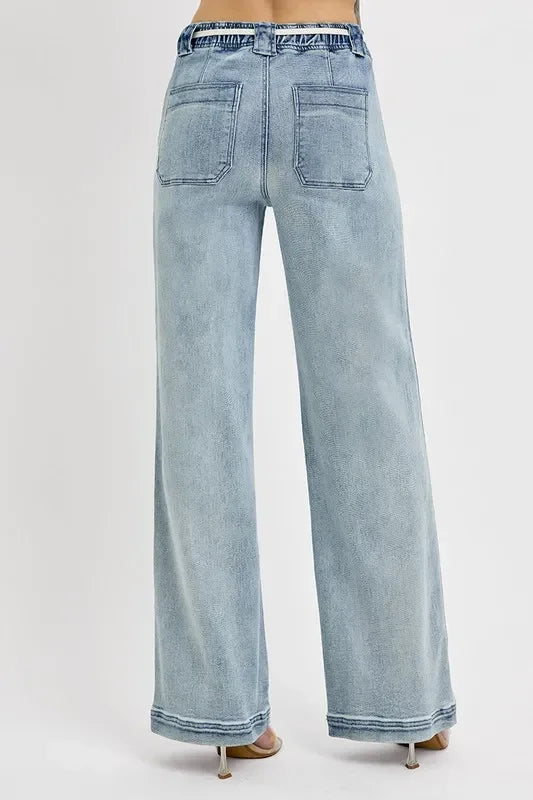 Wide-leg light wash denim jeans with back patch pockets, shown from rear view on model.