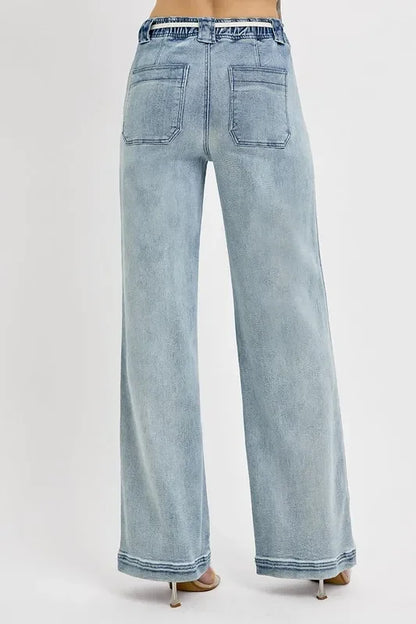 Wide-leg light wash denim jeans with back patch pockets, shown from rear view on model.