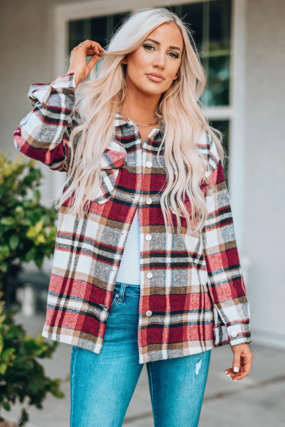 Woman wearing a red plaid button-up jacket with blue jeans, standing outdoors