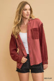 Woman wearing relaxed red clay button-up shirt with textured sleeves and black denim shorts.