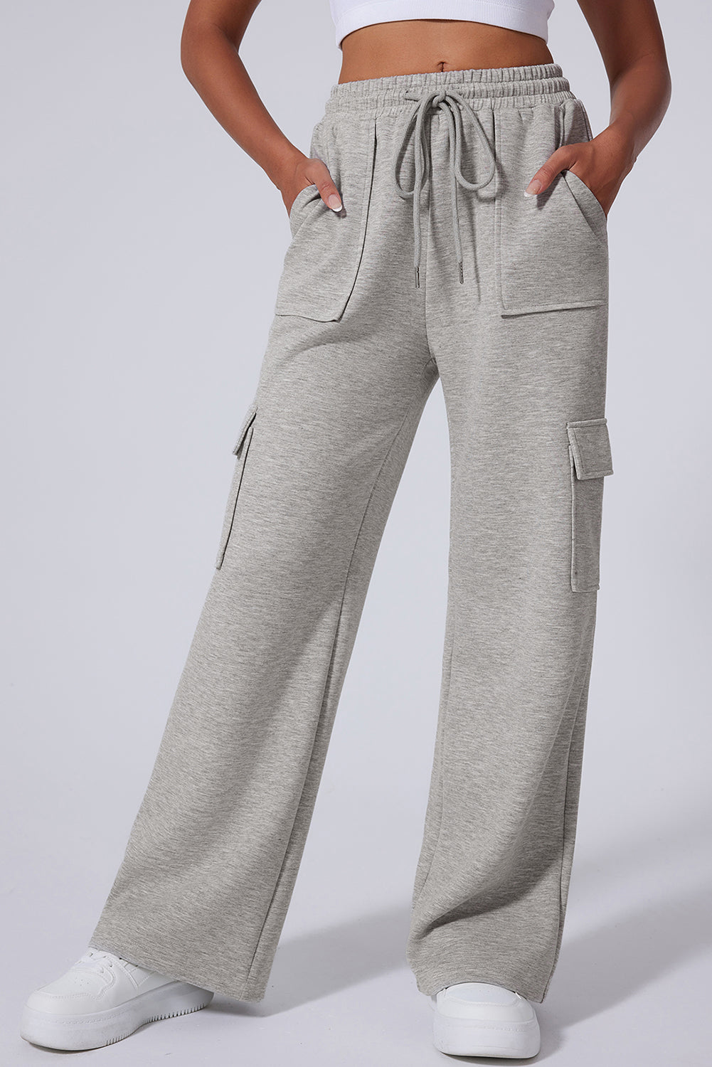 Light grey wide-leg sweatpants with cargo pockets and drawstring waist, worn with white sneakers