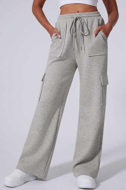 Light grey wide-leg sweatpants with cargo pockets and drawstring waist, worn with white sneakers