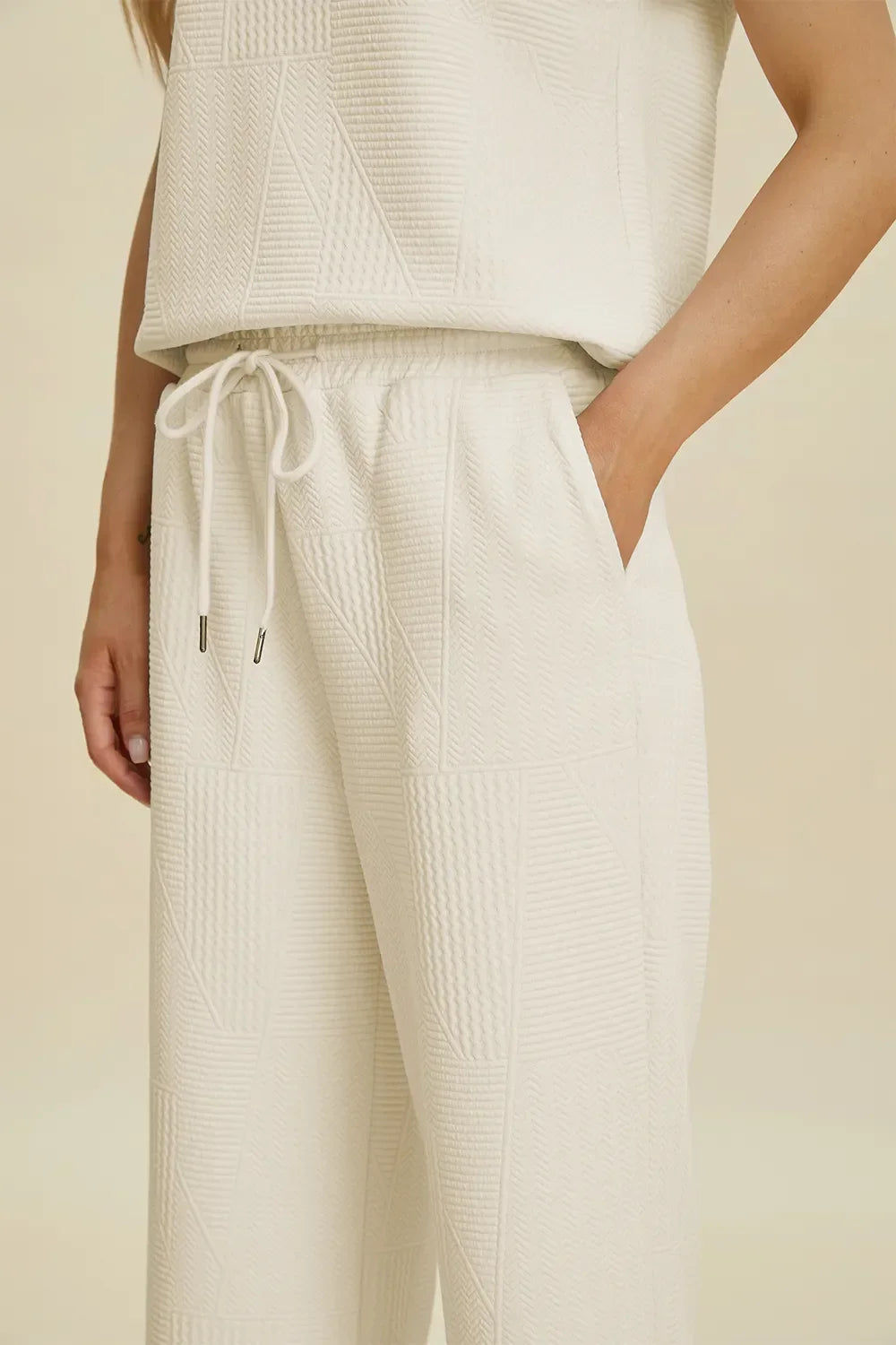 Woman wearing textured cream drawstring pants with pockets and relaxed fit