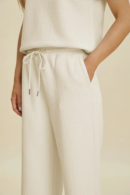 Woman wearing textured cream drawstring pants with pockets and relaxed fit