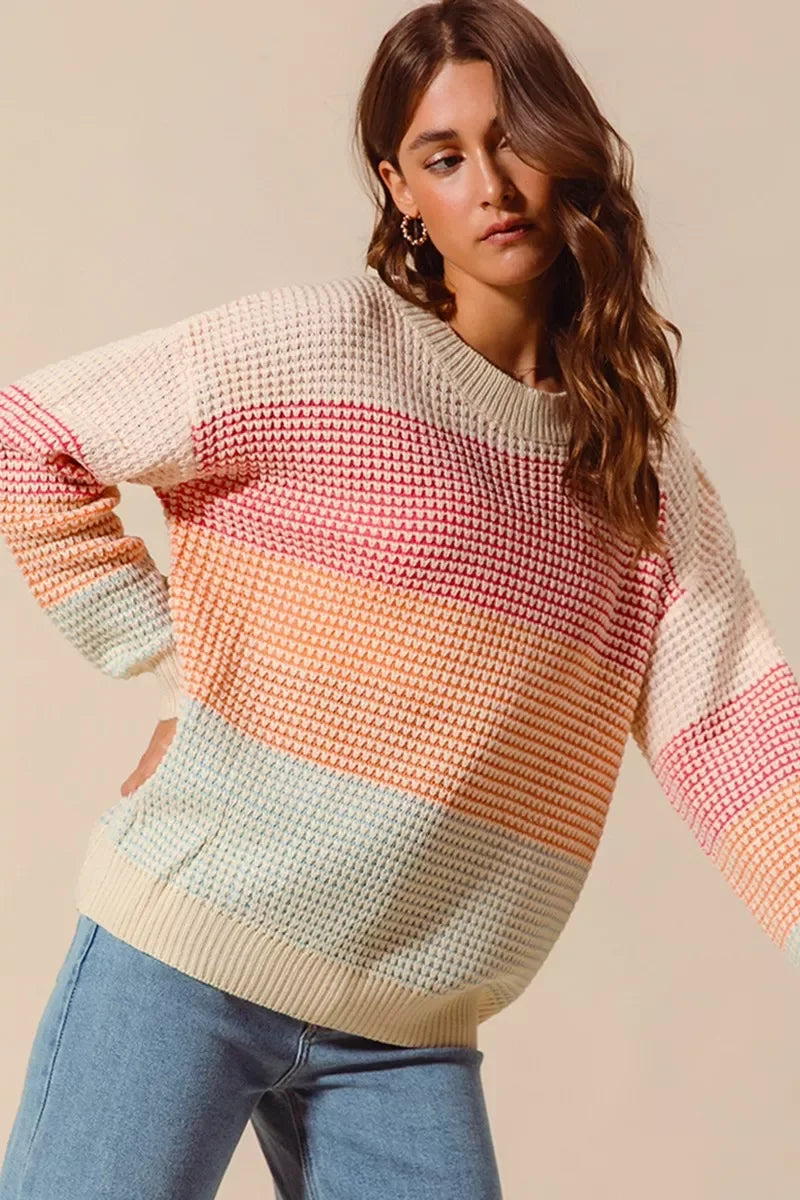 Woman wearing a relaxed fit pastel striped knit sweater with light blue jeans