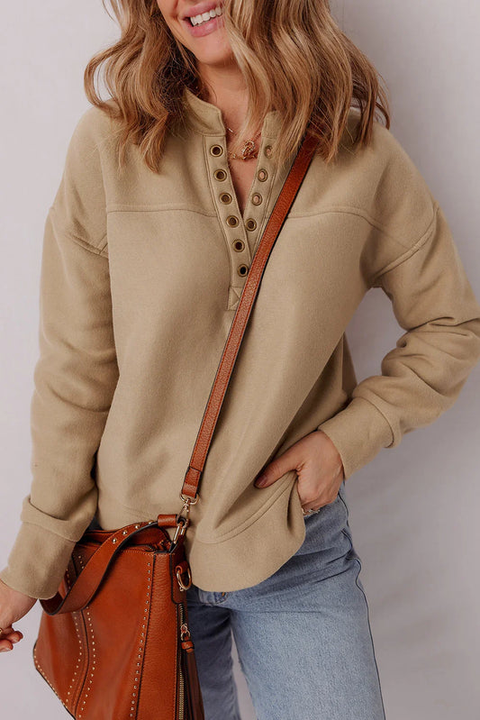 Woman wearing a beige button-collar pullover, light denim jeans, and a brown leather crossbody bag