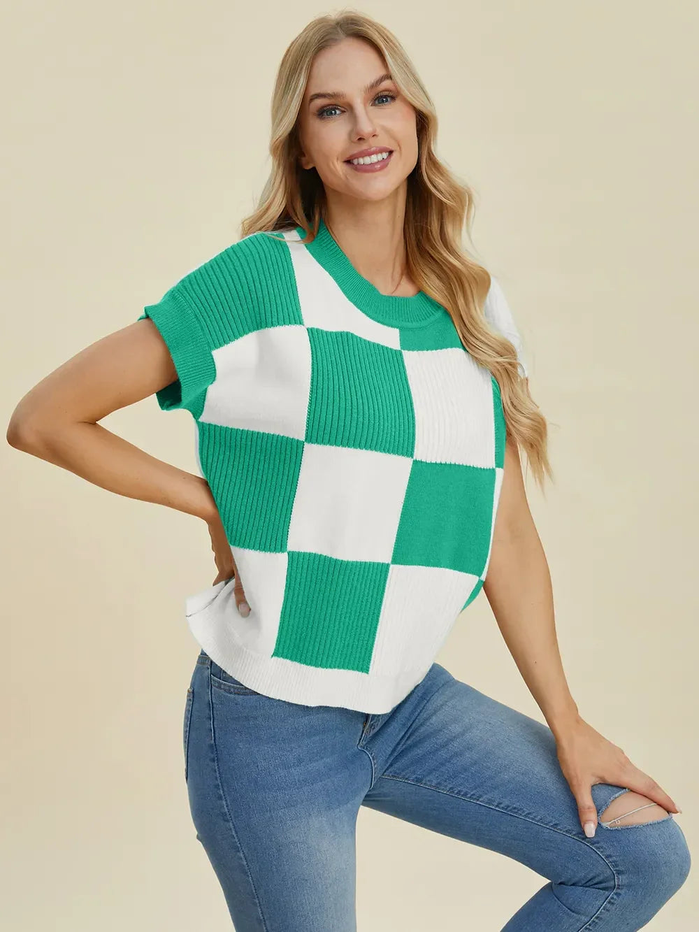 Woman wearing green and white checkered knit top with short sleeves and blue jeans