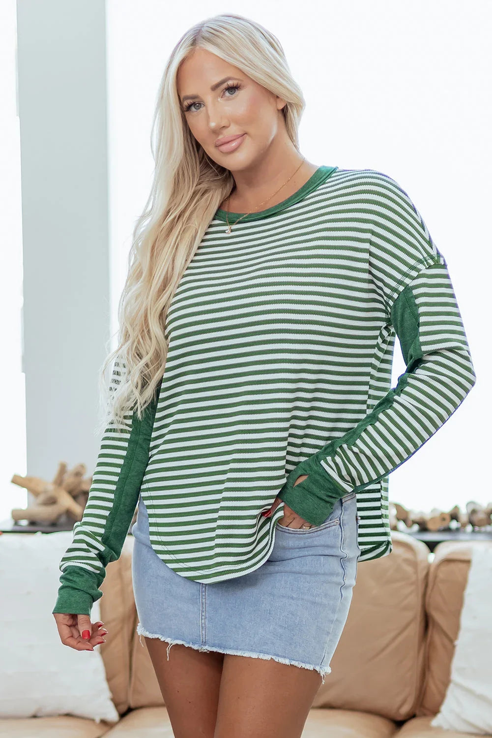 Woman wearing green and white striped long sleeve top with light denim mini skirt