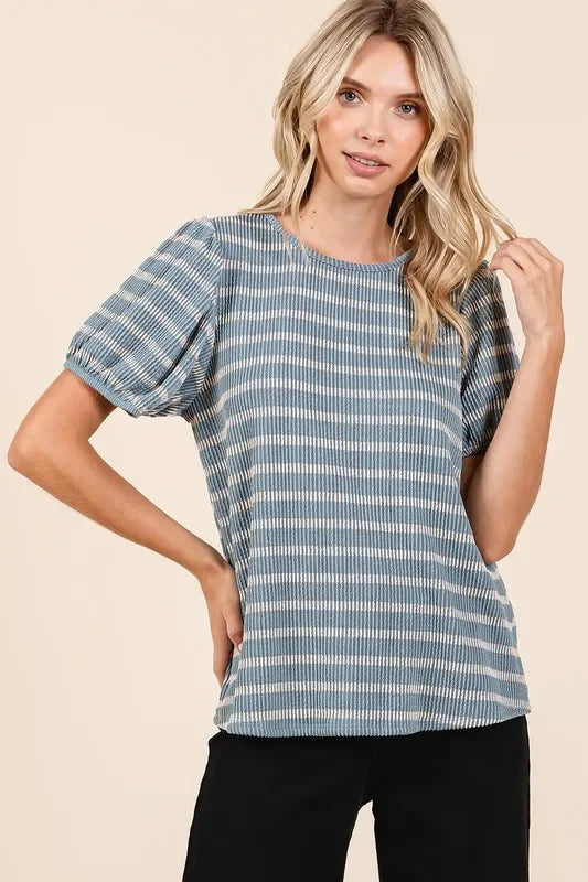 Woman wearing a blue striped puff sleeve blouse with relaxed fit, paired with black pants.