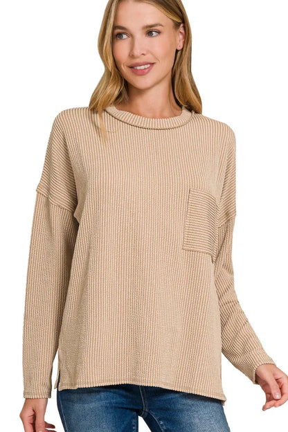Woman wearing a light mocha ribbed knit long sleeve top with front pocket and relaxed fit.