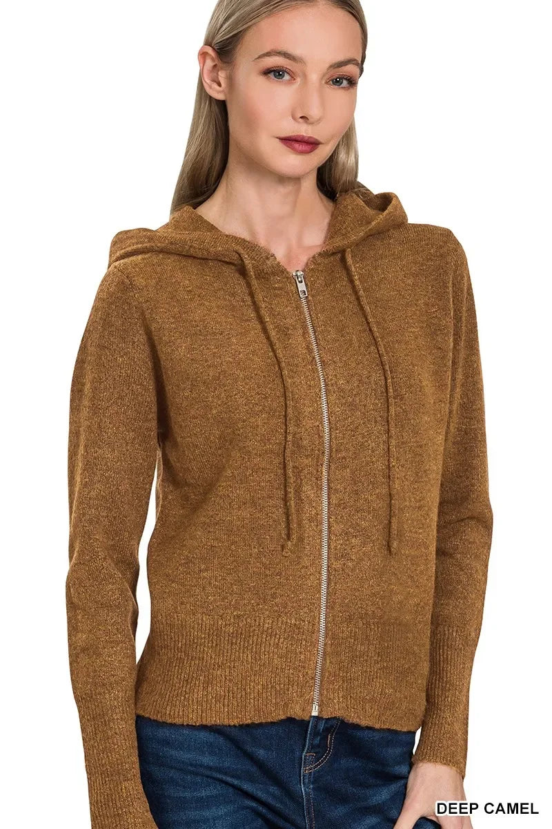 Woman wearing a deep camel zip-up hooded sweater with drawstrings and blue jeans