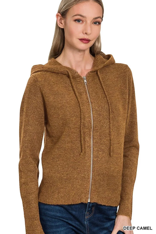 Woman wearing a deep camel zip-up hooded sweater with drawstrings and blue jeans