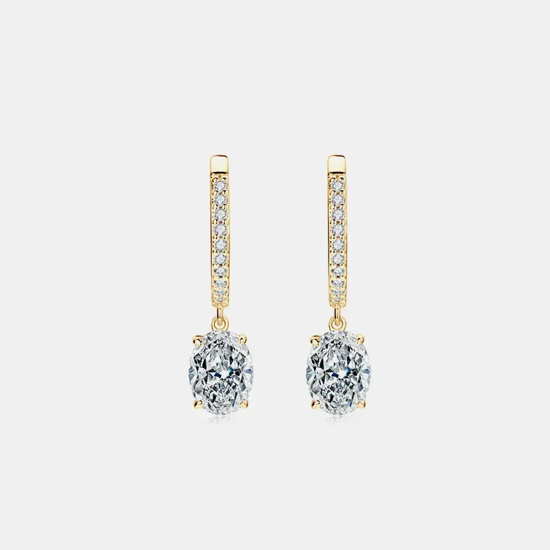 Gold drop earrings with oval clear gemstones and pavé accents on white background