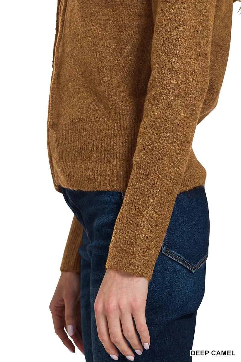 Woman wearing deep camel knit sweater with long sleeves and dark denim jeans