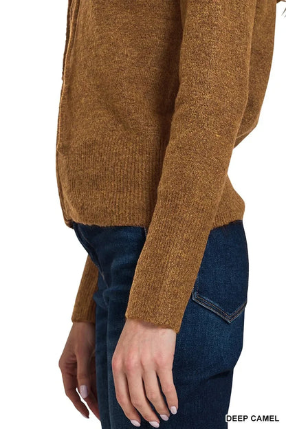 Woman wearing deep camel knit sweater with long sleeves and dark denim jeans