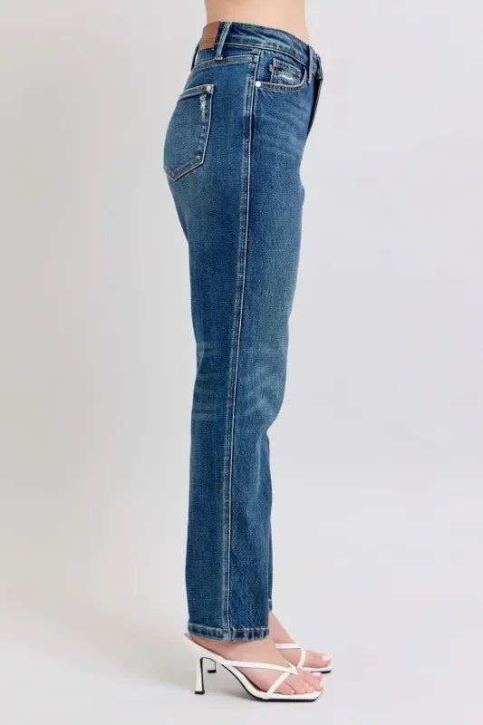Side view of woman wearing high-waisted straight-leg blue jeans and white heeled sandals