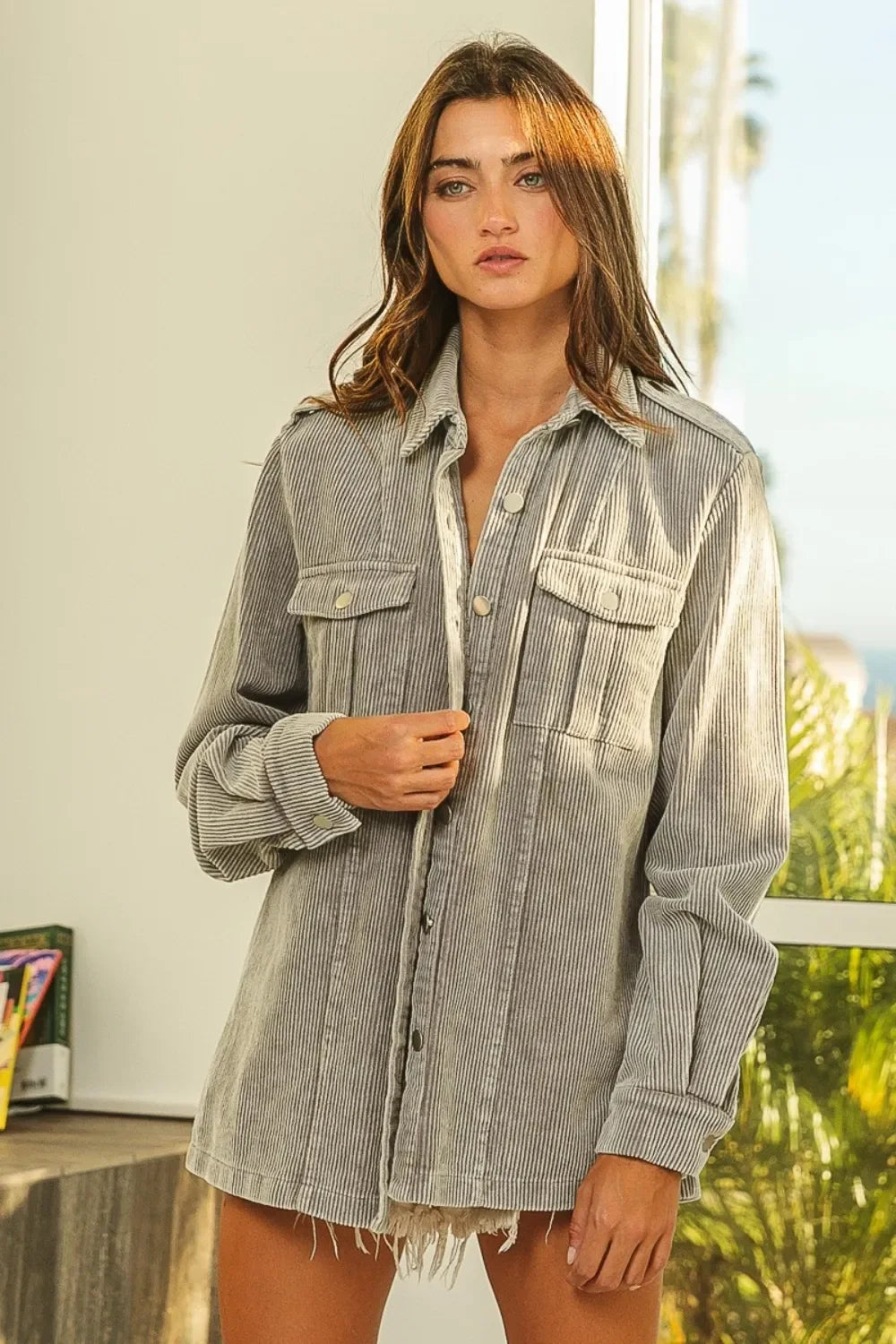 Woman wearing a relaxed-fit striped corduroy shirt jacket with pockets and frayed hem.