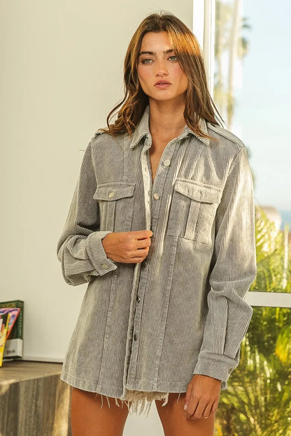 Woman wearing a relaxed-fit striped corduroy shirt jacket with pockets and frayed hem.