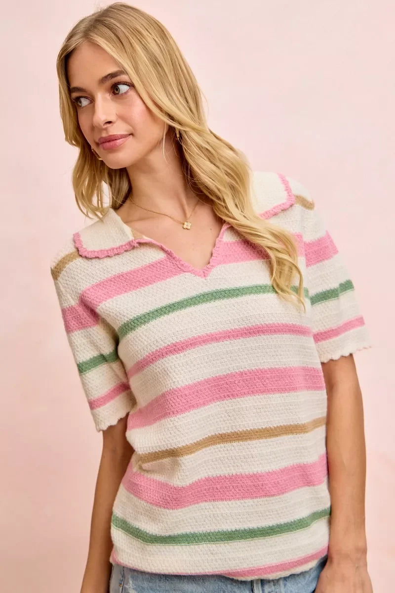 Woman wearing a short sleeve collared knit top with pink, green, and beige stripes.